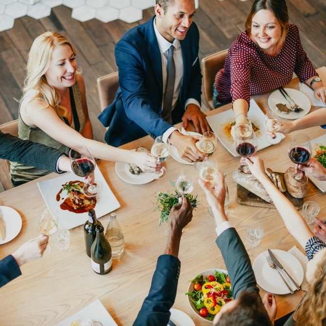 Dîner de groupe : Amis trinquant au vin dans un restaurant Groupe d'amis souriants trinquant avec des verres de vin lors d'un repas festif dans un restaurant moderne.